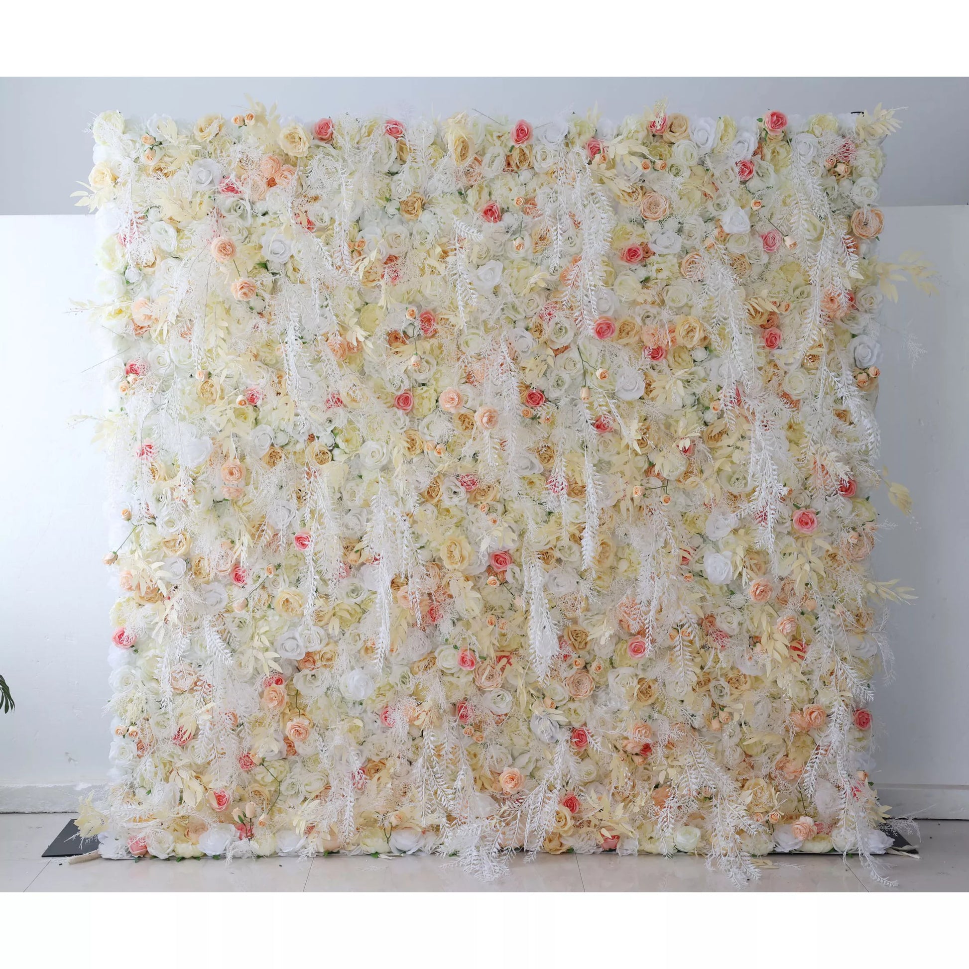 This flower wall is a delicate blend of cream, white, and soft pink artificial blooms. It features roses, tiny flowers, and feathery foliage, creating a light, airy texture. Subtle red accents add charm, making it perfect for weddings or elegant events. It exudes a romantic, ethereal vibe as a dreamy backdrop. 