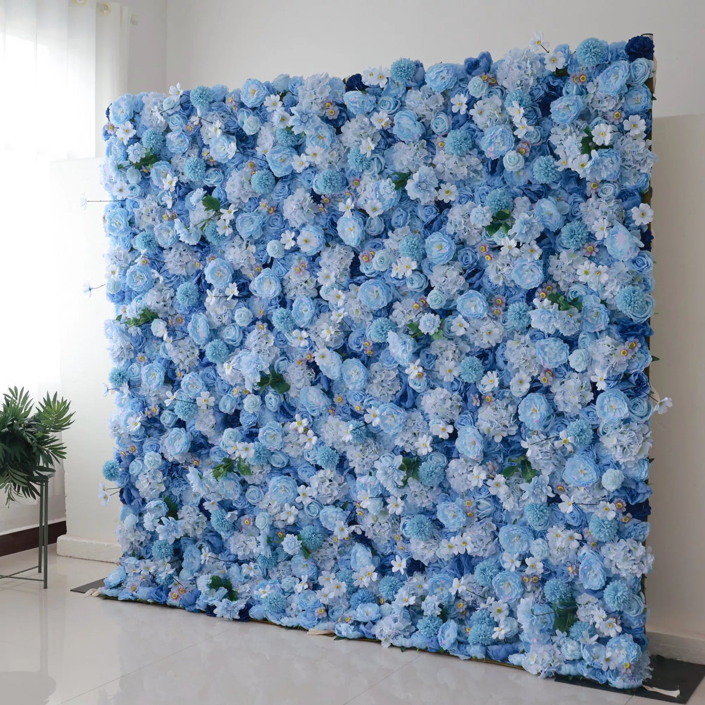 Valar Flowers' Azure Blooms Gala: A large artificial flower wall in soft blue tones, featuring dense clusters of blooms like roses and hydrangeas, mixed with tiny white flowers and green foliage. The harmonious color palette creates a serene, elegant backdrop, perfect for adding a refined, decorative touch to events or spaces. 
