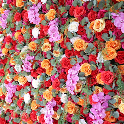This image showcases a vibrant floral arrangement by Valar Flowers. It features a dense cluster of artificial flowers in a rich palette of red, orange, pink, and white, including roses and other complementary blooms, interspersed with lush green foliage. The flowers are intricately arranged to create a lush, textured, and visually striking display. Perfect for adding a touch of energy and elegance to events or spaces, the arrangement exudes a lively and sophisticated atmosphere.