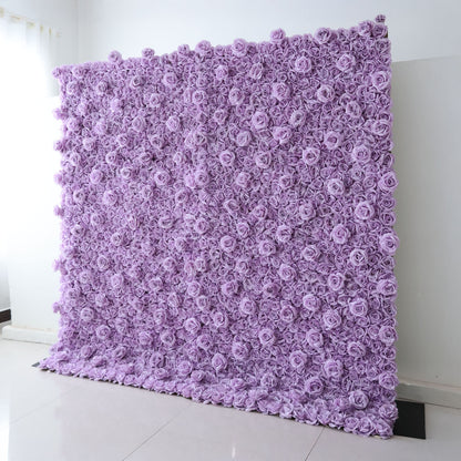 A tall, square Valar Flowers floral wall panel leans against a clean white wall on light tile flooring. It is densely covered in uniform, soft lavender fabric roses, creating a seamless, textured monochromatic surface. This sleek, minimalist design is ideal for wedding backdrops, purple-themed parties, or elegant photo booth setups.