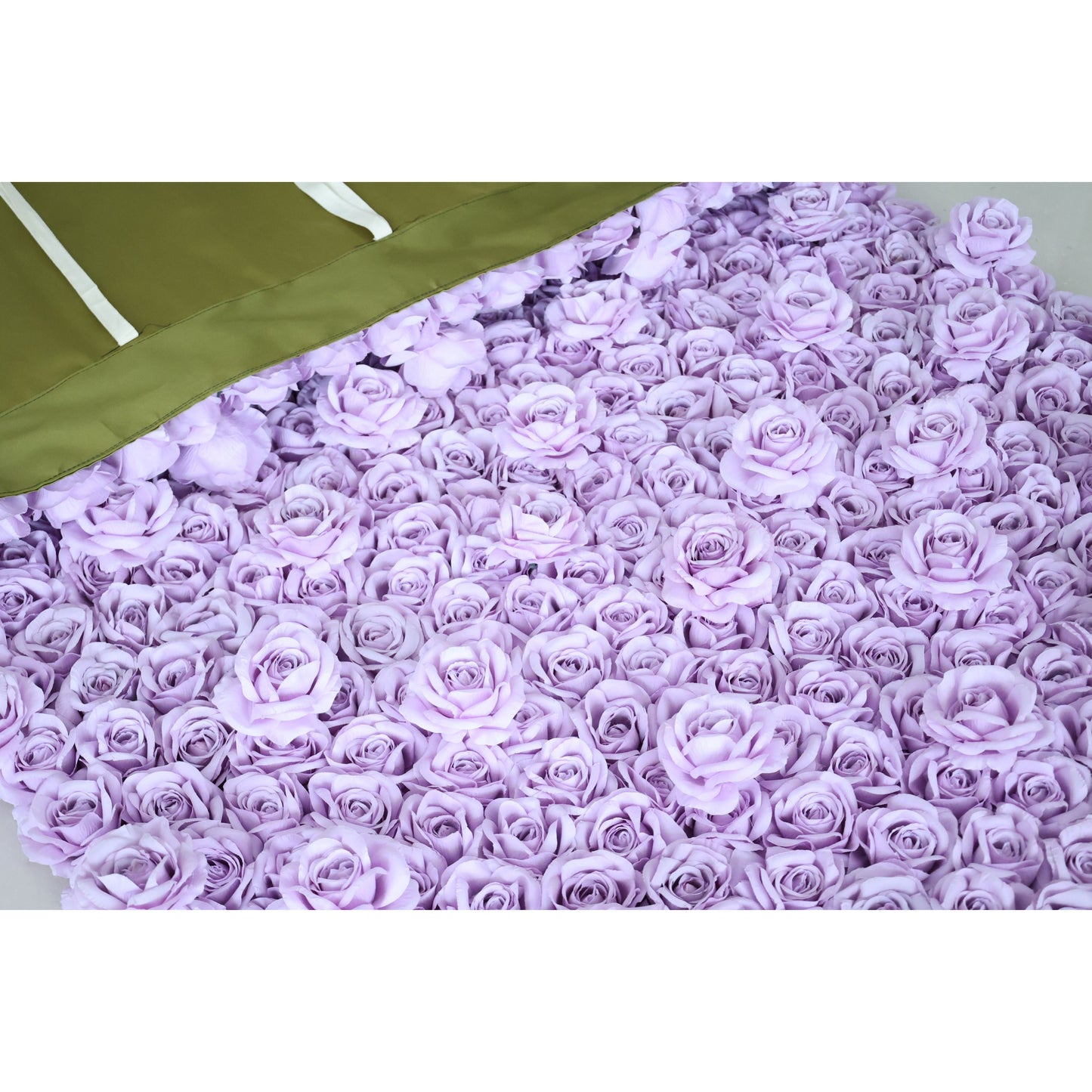 A close-up of a Valar Flowers lavender fabric rose panel, spread flat to showcase its ultra-dense, uniform 3D rose texture. The top corner reveals the olive-green backing with white hanging ribbons, highlighting the product’s durable construction and easy-install design—ideal for quick wedding, party, or photo booth decor setup.