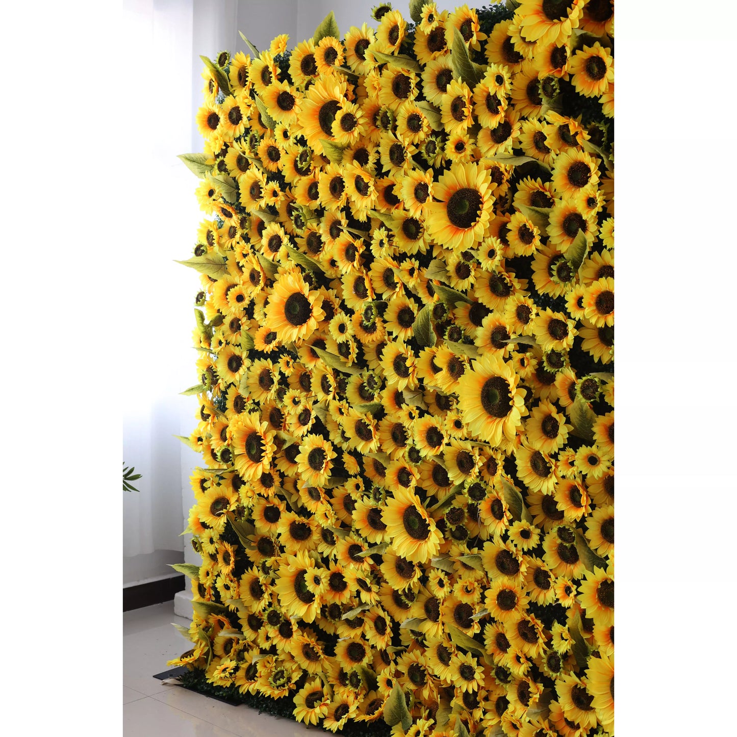 This flower wall features a dense arrangement of artificial sunflowers. Bright yellow petals, dark brown centers, and green leaves create a vibrant, sunny vibe. Ideal for events, it adds warmth and positivity, with varying bloom sizes for visual depth. A lively backdrop perfect for photos or decor. 