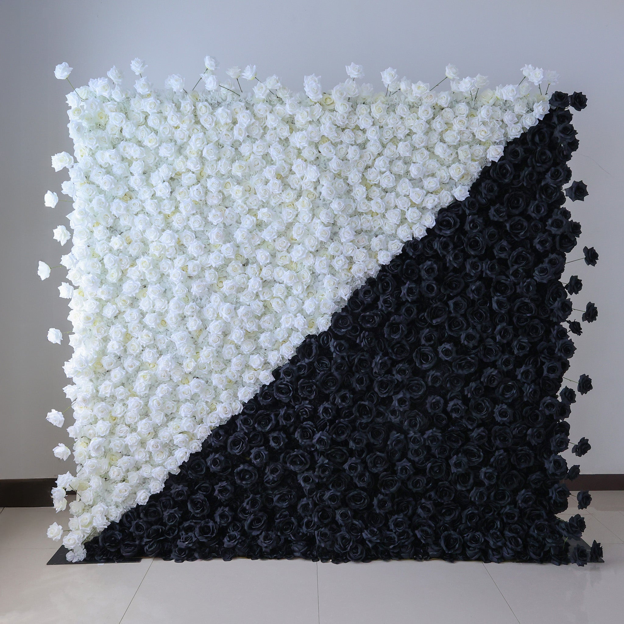 This photo showcases a striking floral wall composed entirely of artificial roses, split diagonally into white and black sections. The stark contrast between the pristine white and bold black creates a modern, dramatic aesthetic. Ideal for avant - garde events, fashion shows, or contemporary decor, this design makes a bold statement. The uniform texture of the faux roses offers a polished, long - lasting display, perfect for adding a touch of high - contrast elegance to any setting.