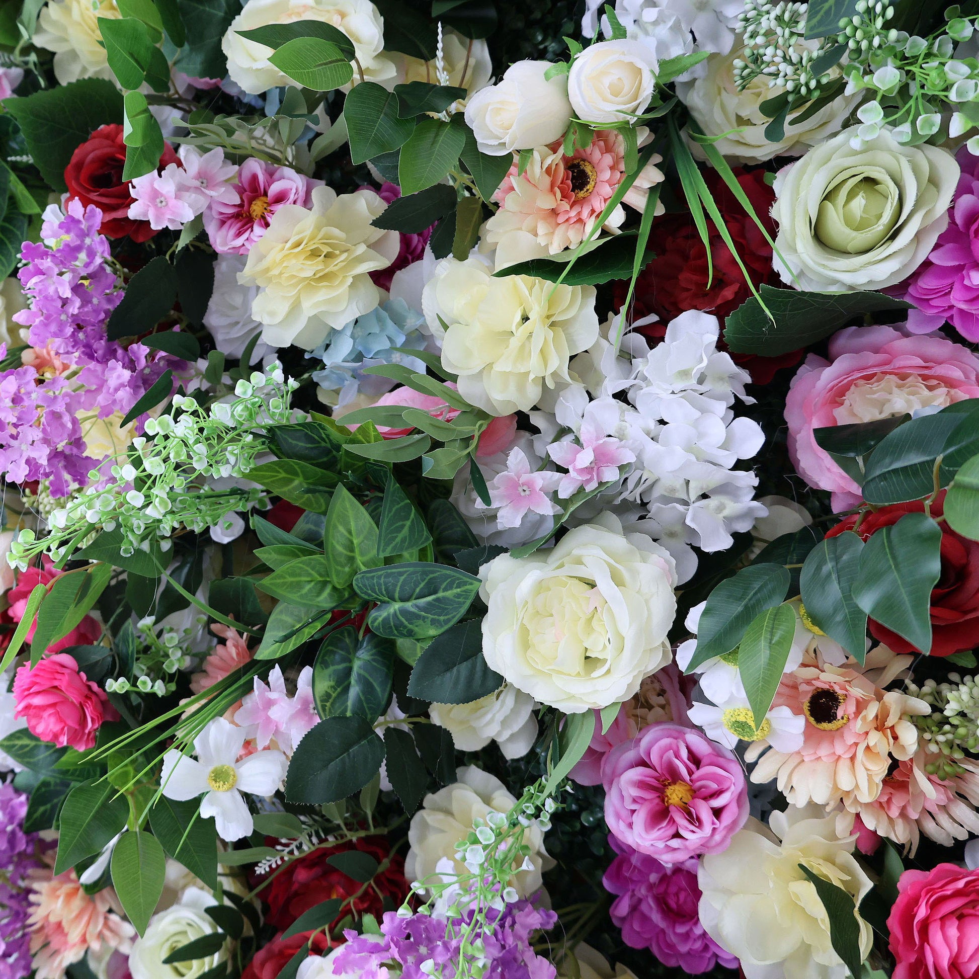 A lush close-up of a Valar Flowers floral wall, showcasing a opulent mix of creamy white garden roses, blush peonies, magenta carnations, deep red blooms, and purple stock, accented with fresh green ivy and delicate filler flowers. The dense, multi-textured arrangement exudes luxury, ideal for high-end wedding photo booths, bridal showers, or elegant event backdrops.