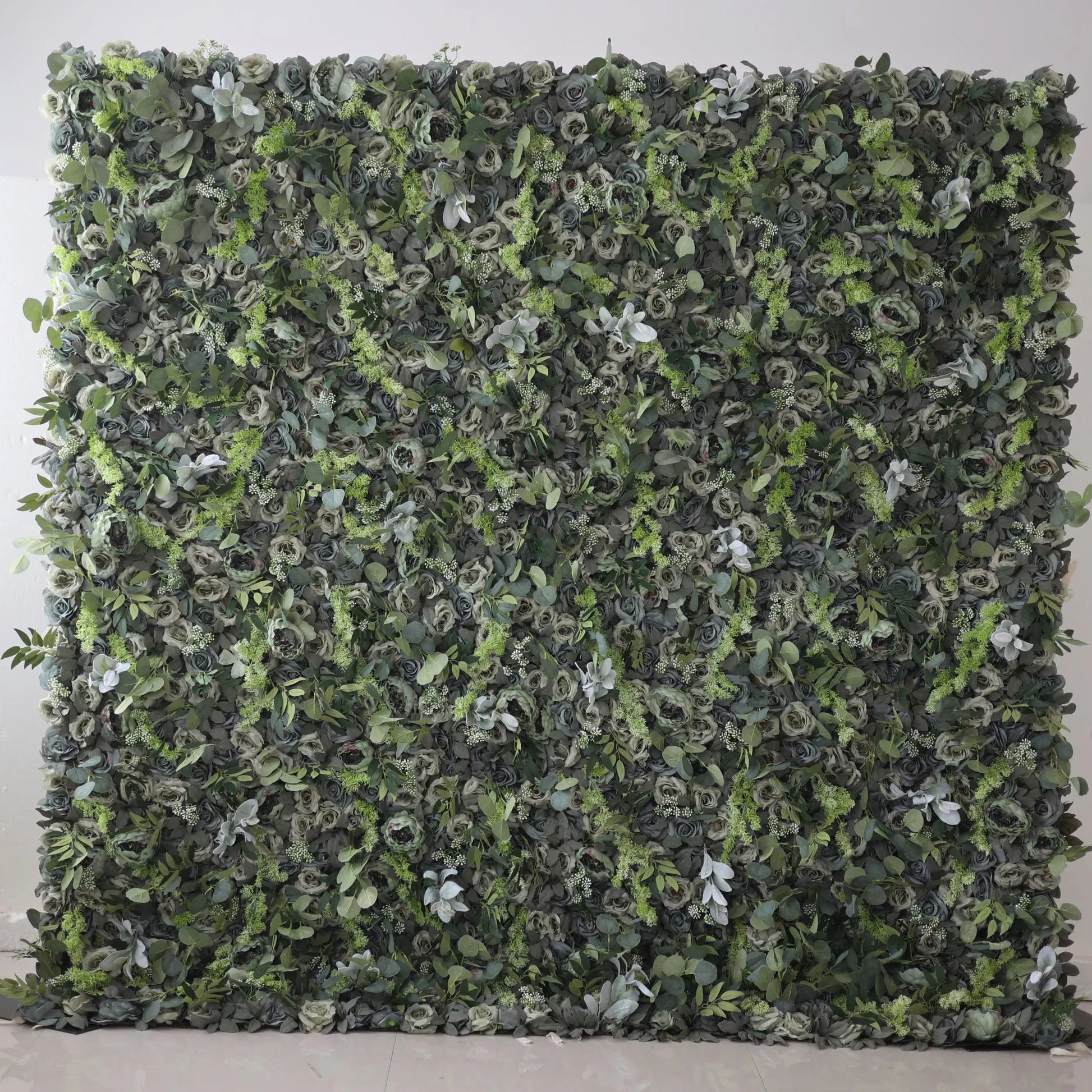 The image shows a lush green wall covered entirely with various types of foliage and flowers. The greenery is dense, with a mix of different shades of green, creating a natural and vibrant appearance.