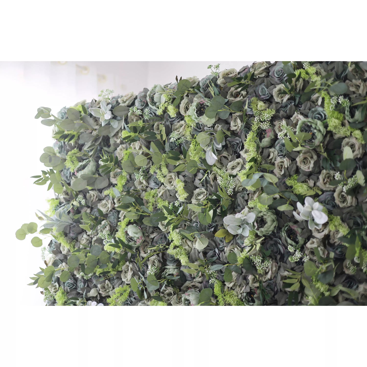 The image shows a lush, green wall adorned with a variety of flowers and foliage. The wall is densely covered with different types of green leaves and blooms, creating a rich and vibrant display. The flowers are interspersed among the greenery, adding pops of color to the overall green backdrop.