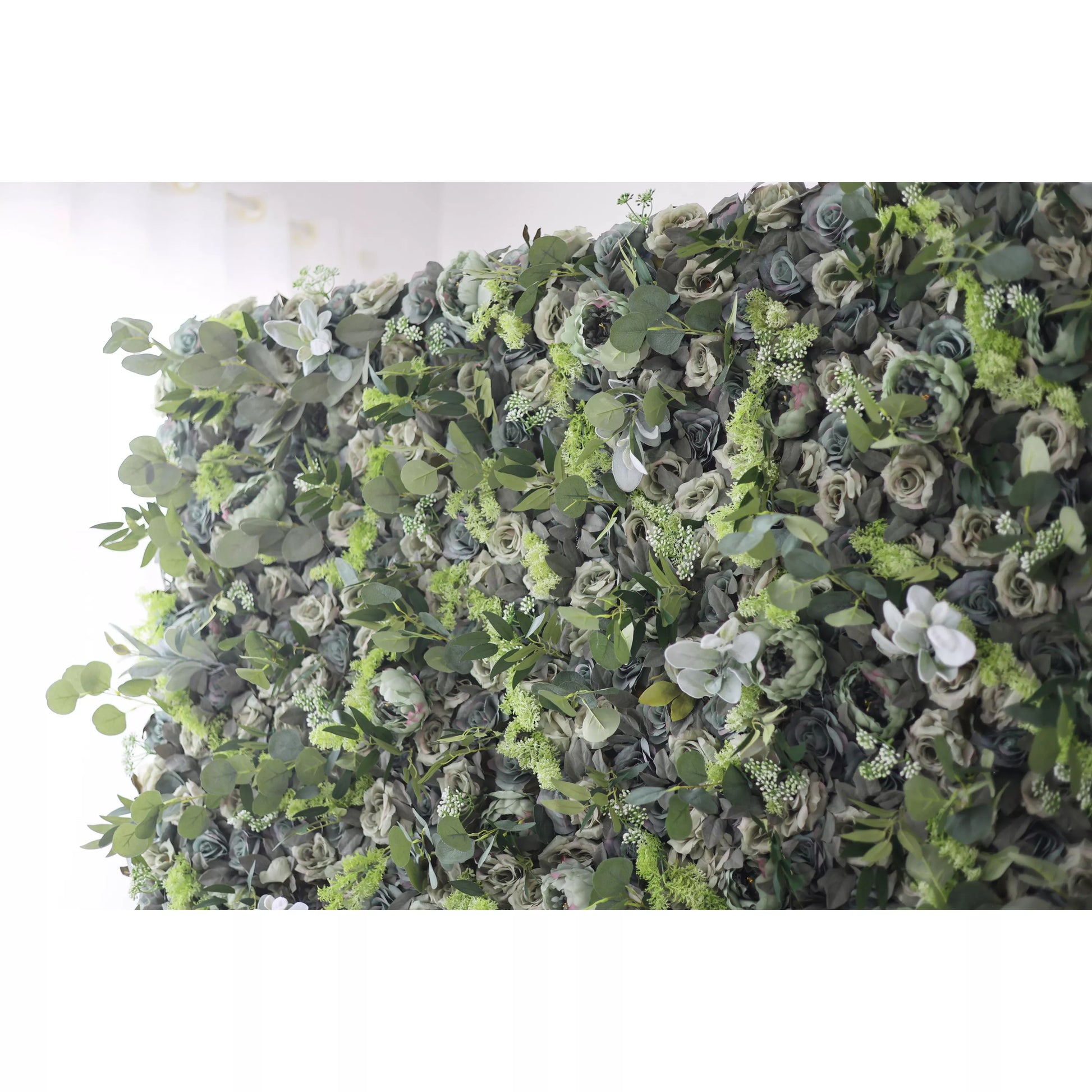 The image shows a lush, green wall adorned with a variety of flowers and foliage. The wall is densely covered with different types of green leaves and blooms, creating a rich and vibrant display. The flowers are interspersed among the greenery, adding pops of color to the overall green backdrop.