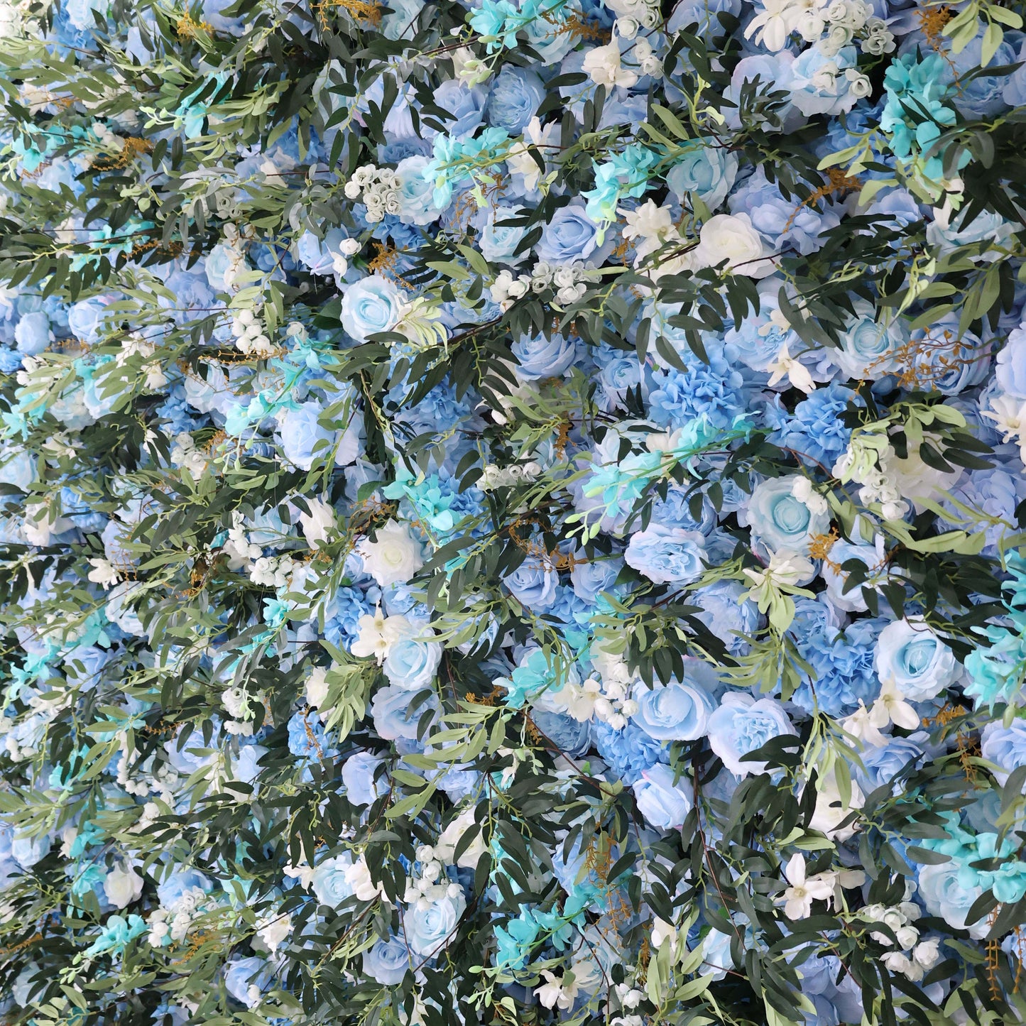This image showcases a stunning floral wall by Valar Flowers. It's densely adorned with artificial flowers in various shades of blue, from light sky blue to deeper hues, along with white blooms. Interspersed with lush green foliage, the arrangement creates a lush, serene, and visually captivating display. Perfect for adding an elegant, nature - inspired touch to events or interior spaces, it exudes a sense of tranquility and beauty.