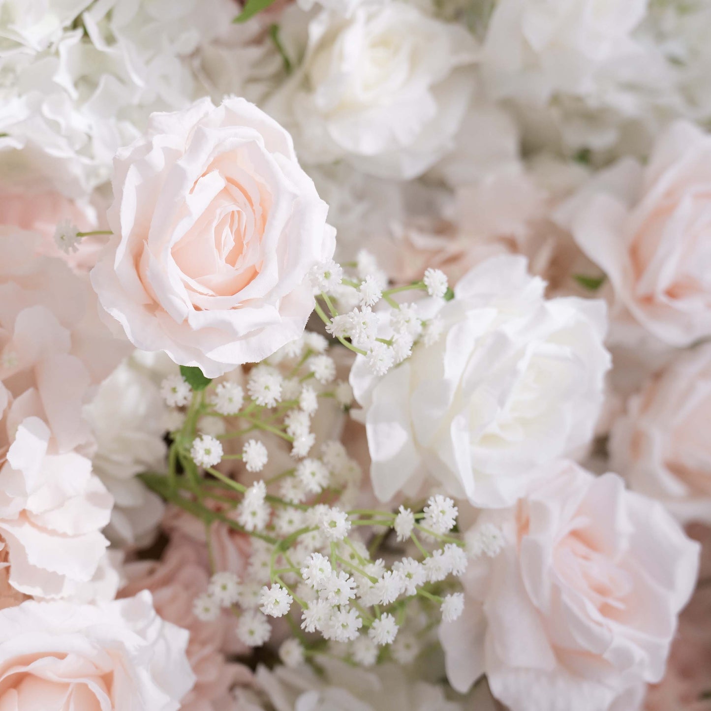 This image depicts a close - up of a floral arrangement that would be part of a backdrop. The flowers include artificial roses in soft shades of white and pale pink, along with delicate sprigs of baby's - breath - like greenery. The color palette is light and airy, creating a romantic and elegant style, perfect for wedding or event decor. 