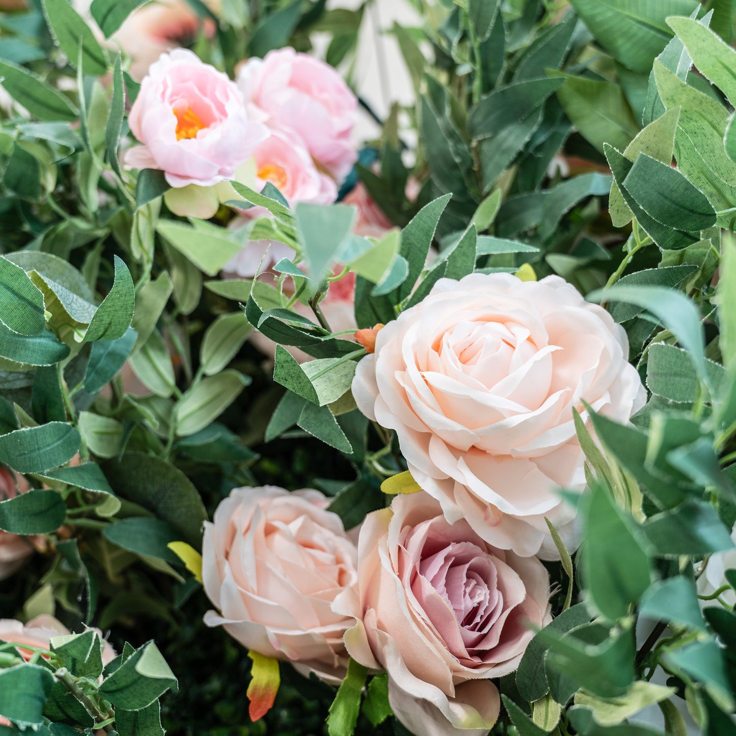 This photo showcases a lush arrangement of pink and light - peach roses intertwined with green foliage. The soft, pastel hues of the roses create a gentle and romantic atmosphere. Ideal for events such as anniversary dinners or a "Blushing Elegance Soirée", it combines the charm of roses with the freshness of greenery, making it a perfect decorative choice for refined and intimate celebrations. 