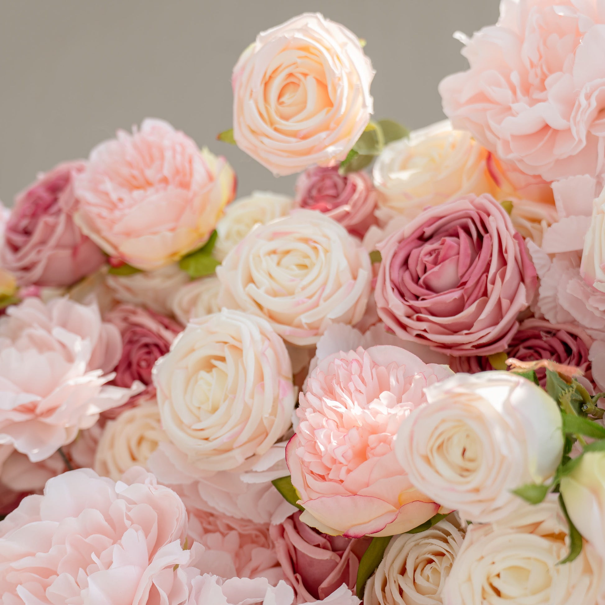 The image showcases a detailed arrangement of artificial flowers. Each petal's texture and color gradient, from soft pink to creamy white, is distinct. The realistic leaves and the precise placement of blooms highlight the craftsmanship.