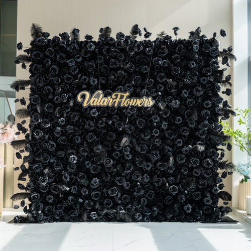 The image features a striking black floral wall with the name "ValarFlowers" prominently displayed in the center. The wall is adorned with black roses and feathers, creating a dramatic and elegant look.
