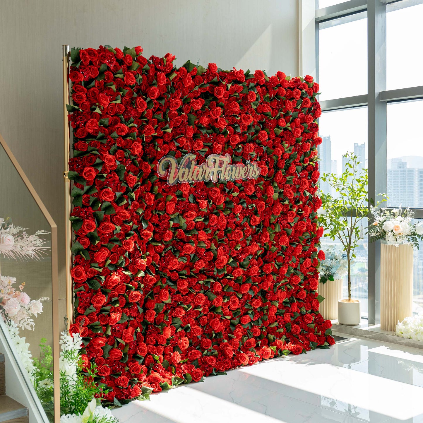 A vibrant red floral wall by ValarFlowers, densely covered with artificial roses, creating a striking and romantic backdrop. 