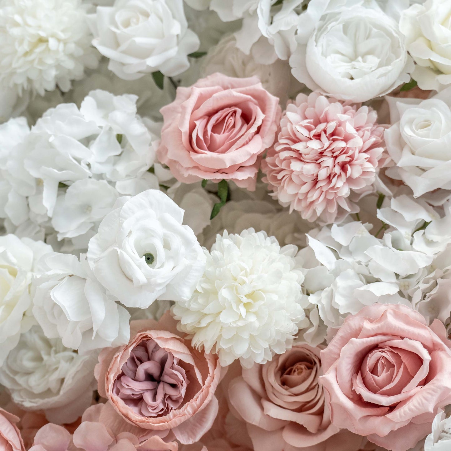 A close - up of a floral arrangement features an assortment of white and soft - pink artificial roses, peonies, and hydrangeas, creating a romantic and textured display. 