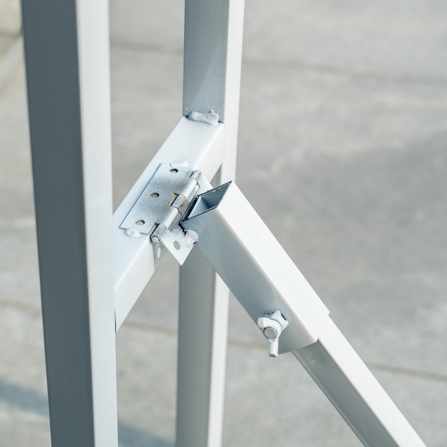 This backdrop stand is a metallic structure with a light - colored finish. It features a hinge mechanism, as seen in the image, which likely allows for folding or adjustment. The stand has a simple, sturdy design with a rectangular frame and diagonal support, secured with bolts and metal plates for stability. 