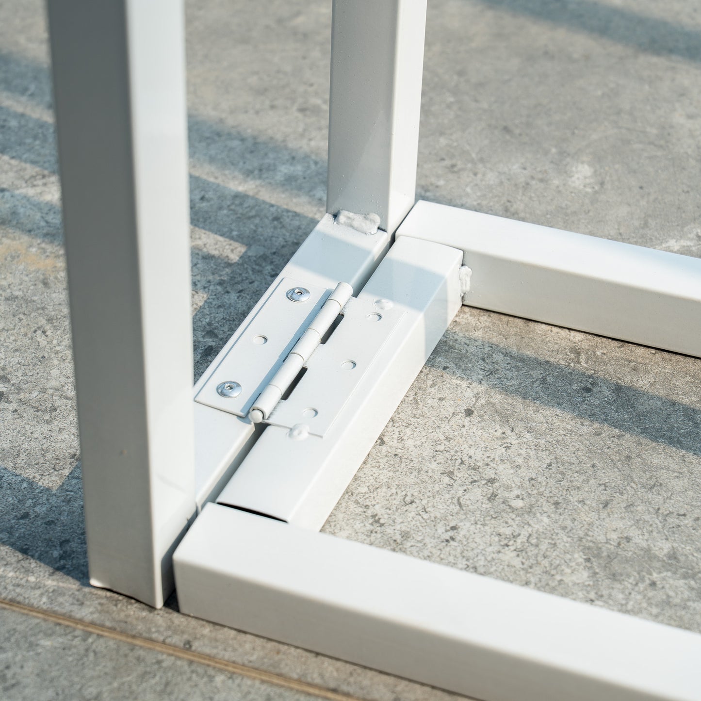 This backdrop stand is a metallic structure with a white finish. It features hinge - type connections at the joints, which likely allow for folding or adjusting the stand's configuration. The sturdy design includes rectangular tubing, and the bolts and hinges suggest it is built for stability and easy assembly or disassembly. 