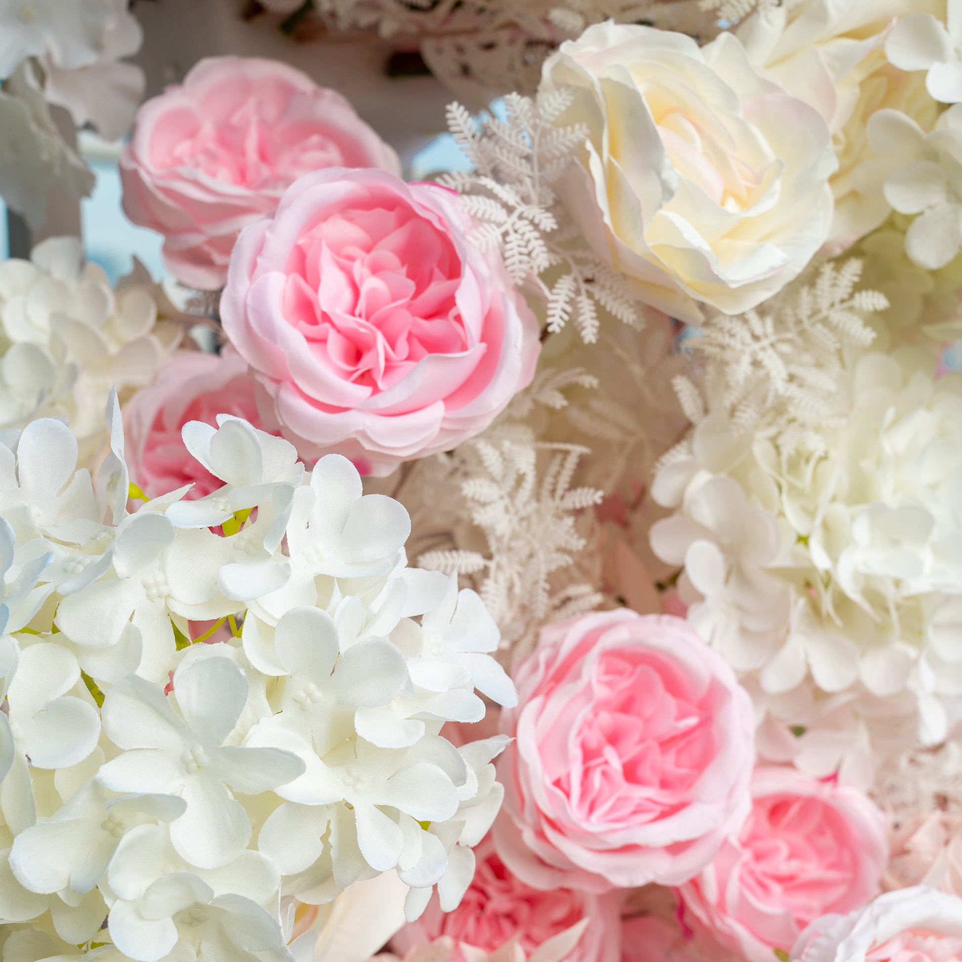 This backdrop features a lush arrangement of artificial flowers. It prominently includes pink and white roses, white hydrangeas, and delicate white fern - like foliage. The color palette is a soft blend of pastel pinks and pure whites, creating a romantic and elegant style, ideal for wedding or bridal events. 