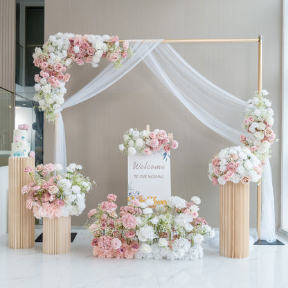 This image showcases a charming wedding welcome setup. A golden - framed arch adorned with white fabric drapery serves as the centerpiece. It is decorated with an abundance of artificial flowers in soft pink, white, and hints of green. A sign that reads &quot;Welcome to our wedding&quot; is prominently displayed. Flower arrangements in tall, pleated vases and on the ground enhance the romantic and elegant atmosphere. 