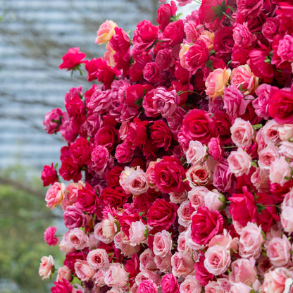 This backdrop is a lush expanse of artificial roses in a vivid blend of deep red and pink hues. The densely - packed blooms create a rich, romantic tapestry, exuding a luxurious and passionate atmosphere, perfect for weddings or upscale events. 