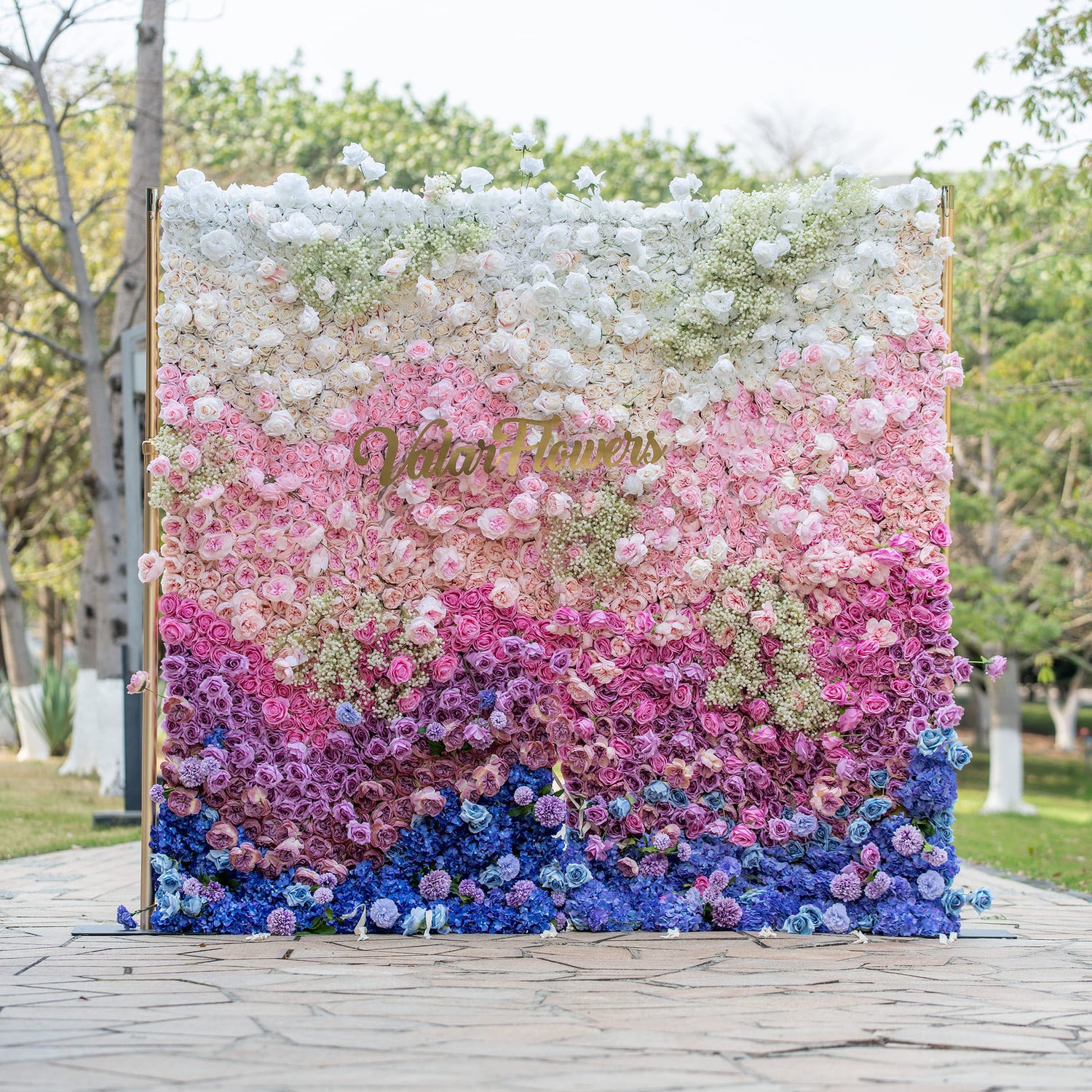 This photo shows a vibrant floral wall with a gradient of colors from white to pink, purple, and blue. It&