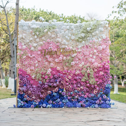 This photo shows a vibrant floral wall with a gradient of colors from white to pink, purple, and blue. It&