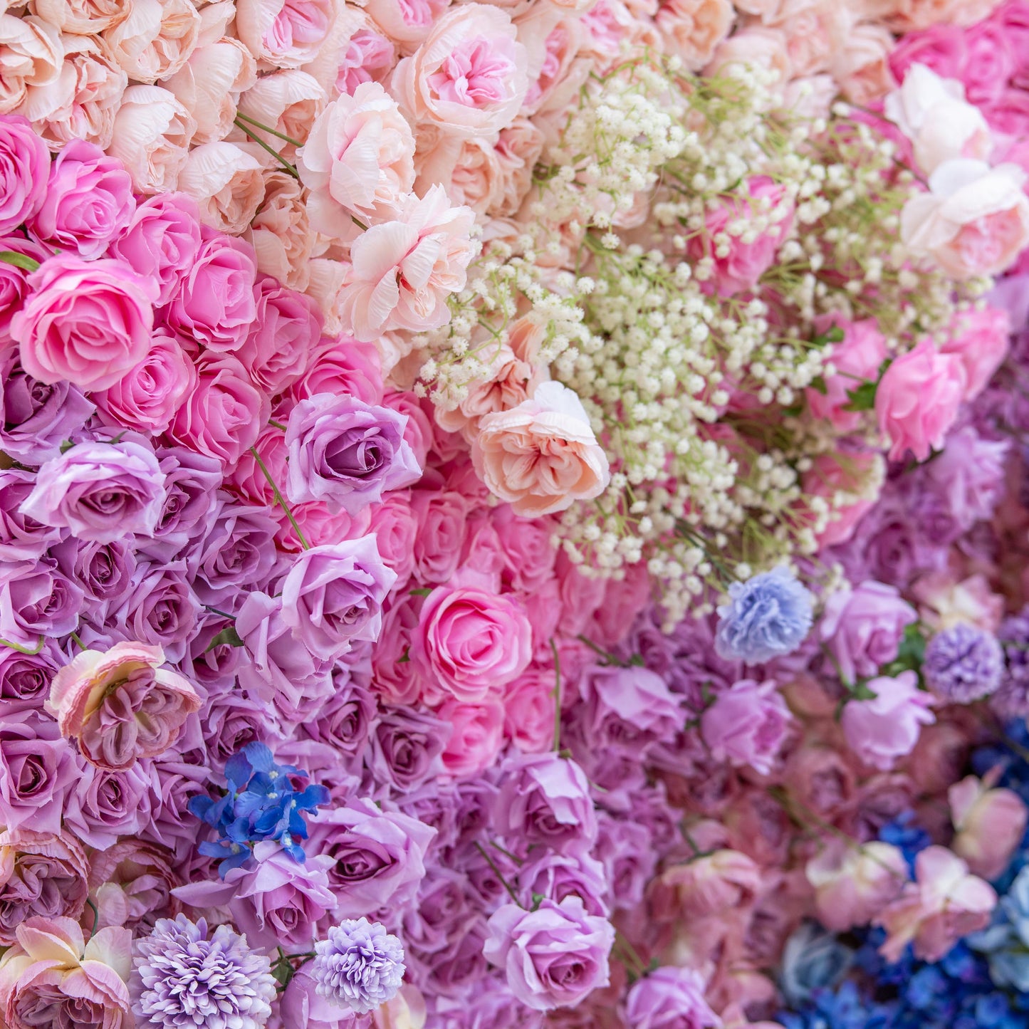 This close - up photo showcases a rich floral arrangement with roses in shades of pink, purple, and peach, along with baby's breath and small blue flowers. The backdrop is blurred, focusing on the blooms. Ideal for weddings or elegant events, it has a romantic, dreamy style. 