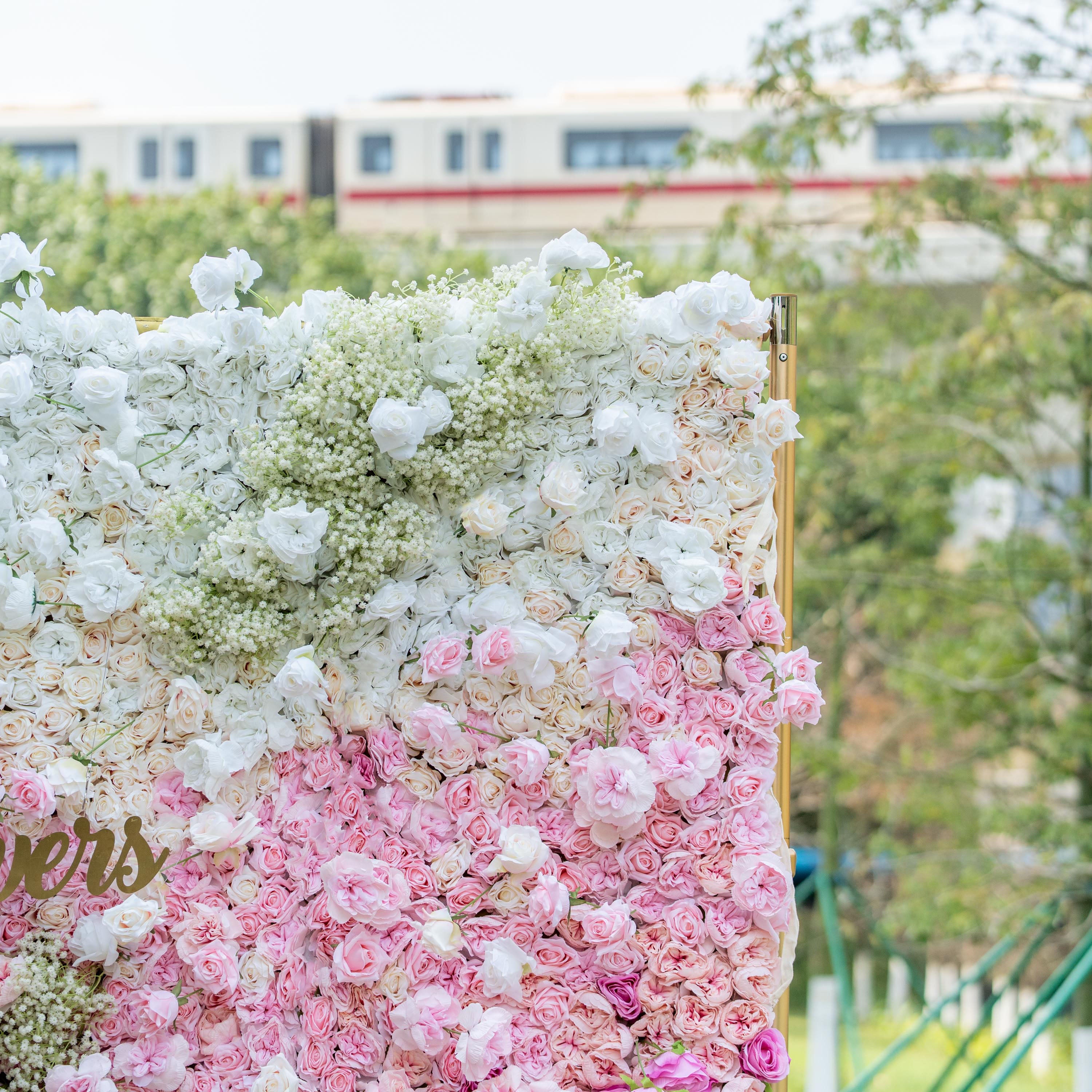 This photo shows a vibrant floral wall with white and pink roses, along with baby&
