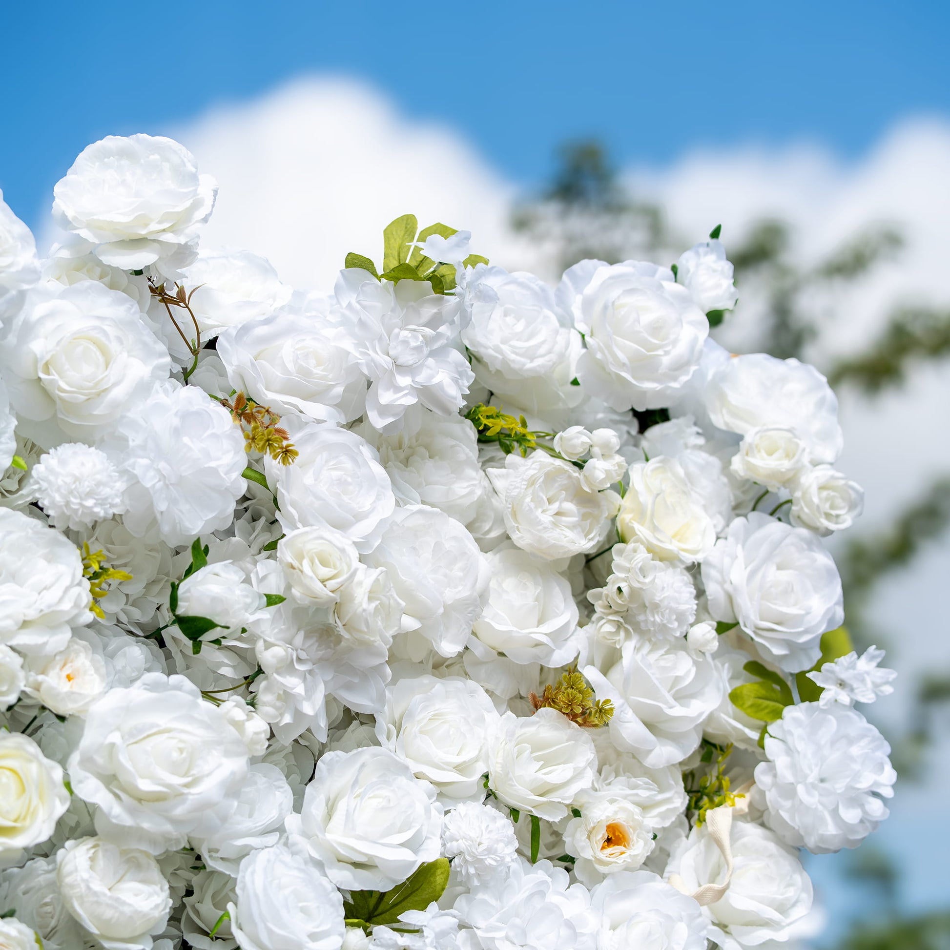 This close - up image showcases a lush arrangement of artificial white flowers, predominantly roses, along with some peony - like blooms and small, round blossoms. Interspersed with green leaves, the color palette is a pure white accented by green. The style is elegant and pristine, exuding a sense of purity and sophistication, ideal for formal events. 