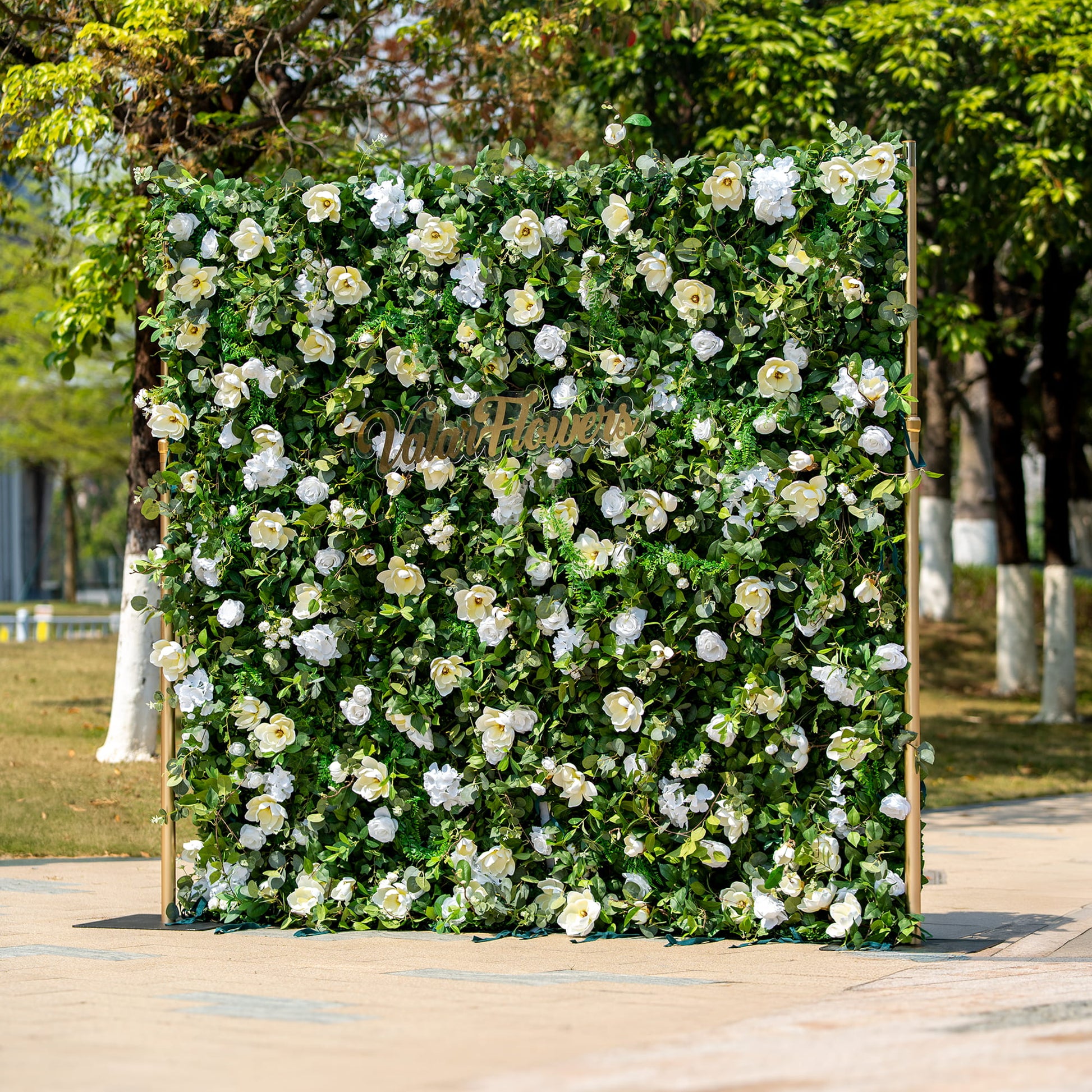 This backdrop is a lush floral wall supported by golden - hued poles. It features an abundance of artificial white roses and other white blooms interspersed among vibrant green foliage. The "Valar Flowers" sign in elegant script adds a touch of sophistication.

The color scheme combines the purity of white flowers with the freshness of green leaves, creating a natural and elegant style. Ideal for weddings, corporate events, or garden - themed parties. 