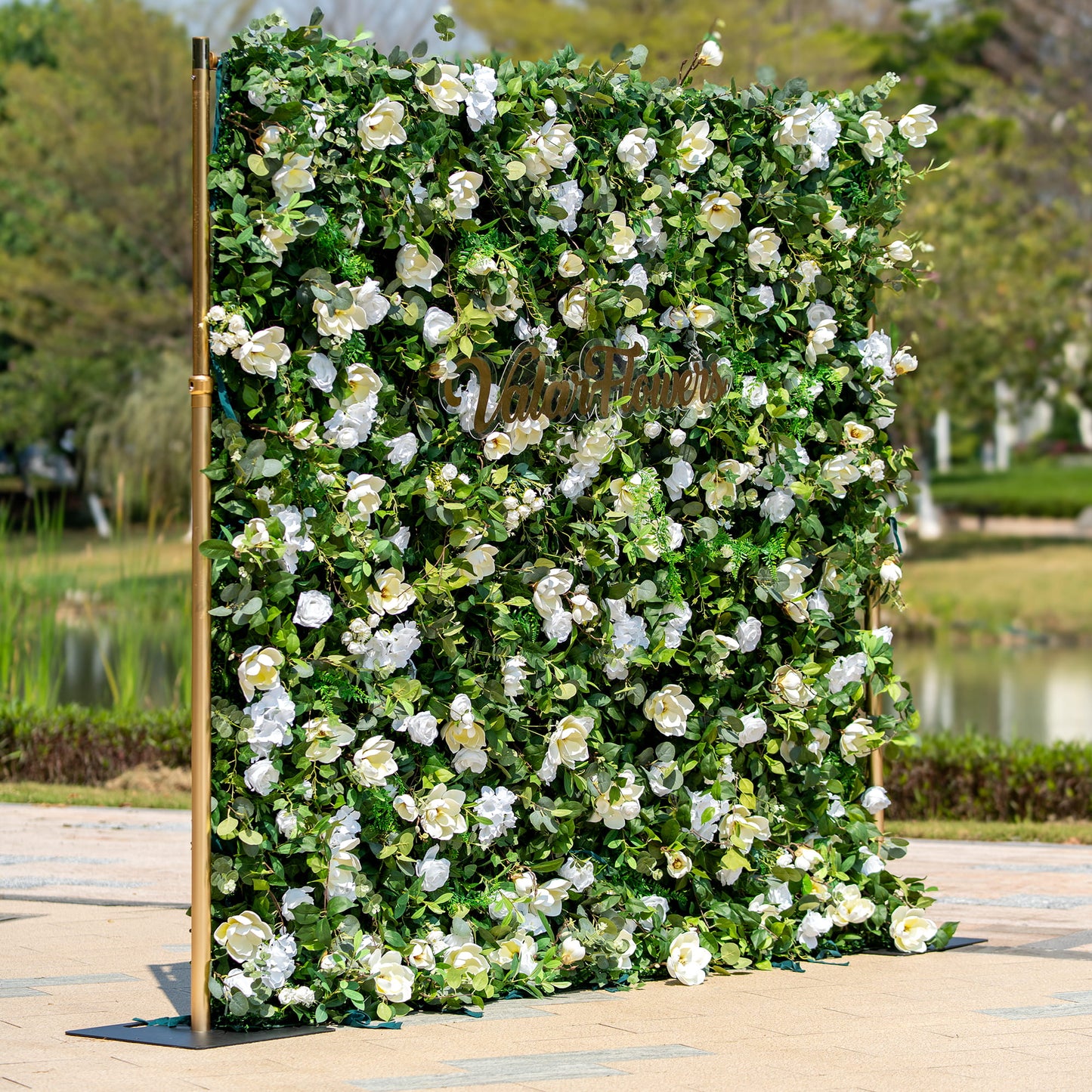 This backdrop is a lush floral wall framed by golden poles. It features an abundance of artificial white roses and other white blooms, interspersed with green foliage. The "Valar Flowers" sign in cursive adds an elegant touch.

The color scheme combines the purity of white flowers with the vibrancy of green leaves, creating a fresh and natural - looking style. Ideal for events like weddings, garden parties, or corporate functions. 