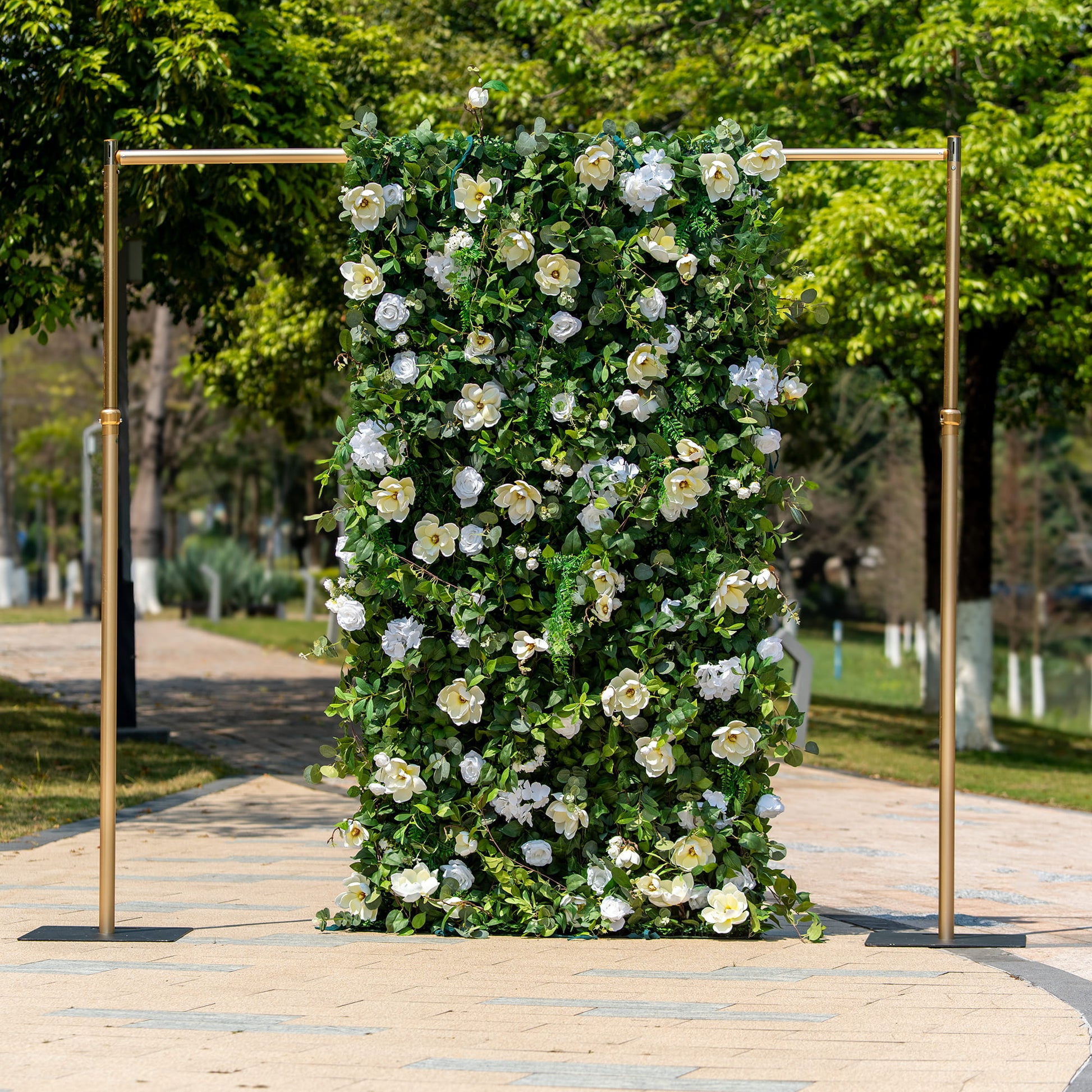 This backdrop features a lush floral wall with a metal frame in a golden hue. The flowers include white roses and magnolia - like blooms, set against a dense backdrop of green foliage.

The color scheme combines the purity of white flowers with the vibrancy of green leaves. The overall style is natural and elegant, perfect for events such as weddings, garden parties, or corporate functions. 