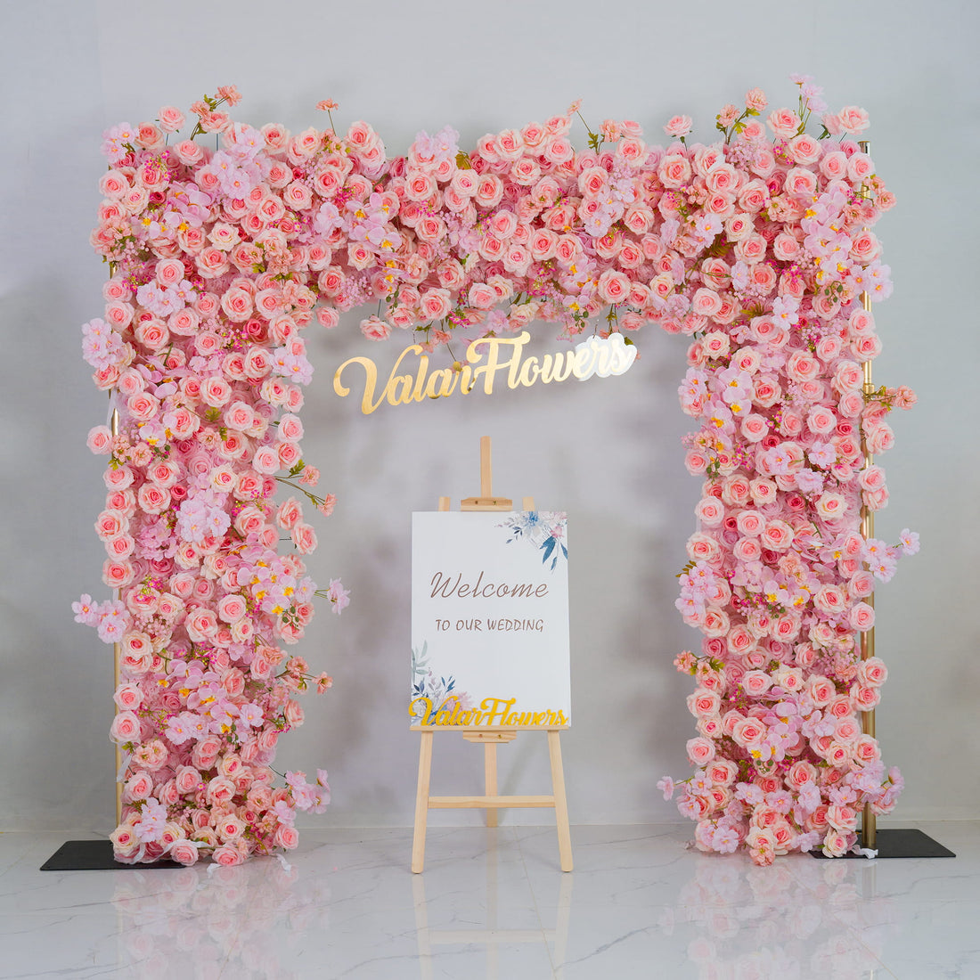 This backdrop features a stunning floral arch made of artificial pink roses and other blossoms in varying shades of pink. The golden - hued "Valar Flowers" signage adds a touch of elegance. 
It is perfect for weddings, as indicated by the "Welcome to our wedding" sign, creating a romantic and inviting atmosphere. It can also be used for bridal showers or other celebratory events to enhance the festive mood.