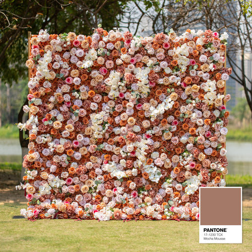 This backdrop features a warm, earthy theme color palette centered around shades of brown, beige, and white, with a Pantone reference of 17 - 1230 TCX (Mocha Mousse). It is densely filled with roses and orchids, perfect for elegant events like weddings or upscale garden parties. 