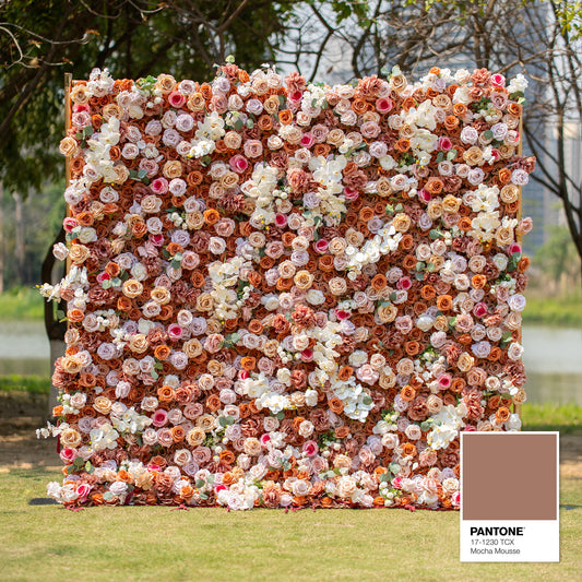 This backdrop features a warm, earthy theme color palette centered around shades of brown, beige, and white, with a Pantone reference of 17 - 1230 TCX (Mocha Mousse). It is densely filled with roses and orchids, perfect for elegant events like weddings or upscale garden parties. 