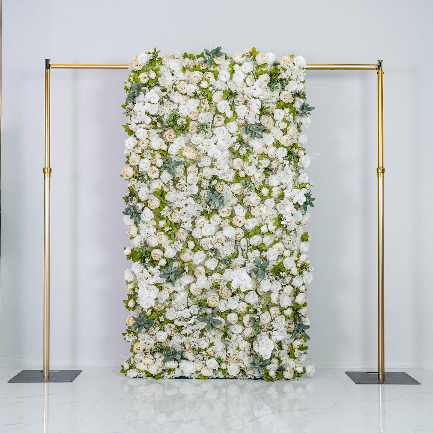 A woman with blonde hair, dressed in a light - colored top and pants, is arranging white flowers on a lush floral backdrop. The backdrop features the text "Valar Flowers" in gold, with numerous white blooms and green foliage. 