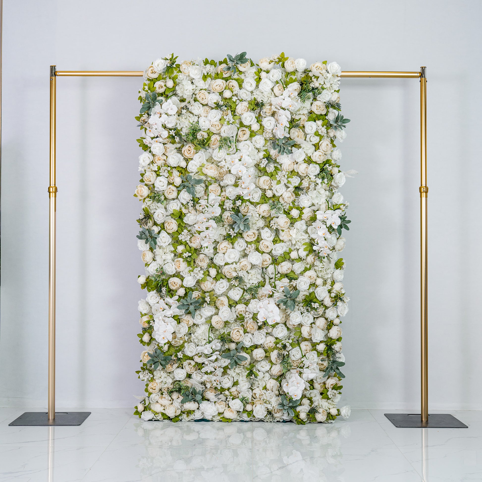 A woman with blonde hair, dressed in a light - colored top and pants, is arranging white flowers on a lush floral backdrop. The backdrop features the text "Valar Flowers" in gold, with numerous white blooms and green foliage. 