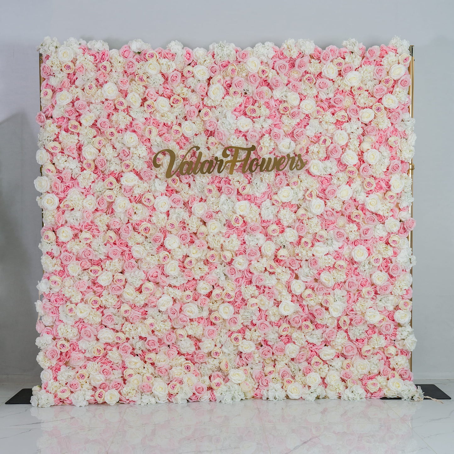 This photo showcases a lush floral backdrop. It is densely covered with a blend of pink and white roses, creating a soft and romantic color scheme. The backdrop also features the text "Valar Flowers" in elegant gold lettering. Ideal for weddings, engagement parties, or bridal showers, it exudes a dreamy and elegant style, perfect for adding a touch of romance to any event. 