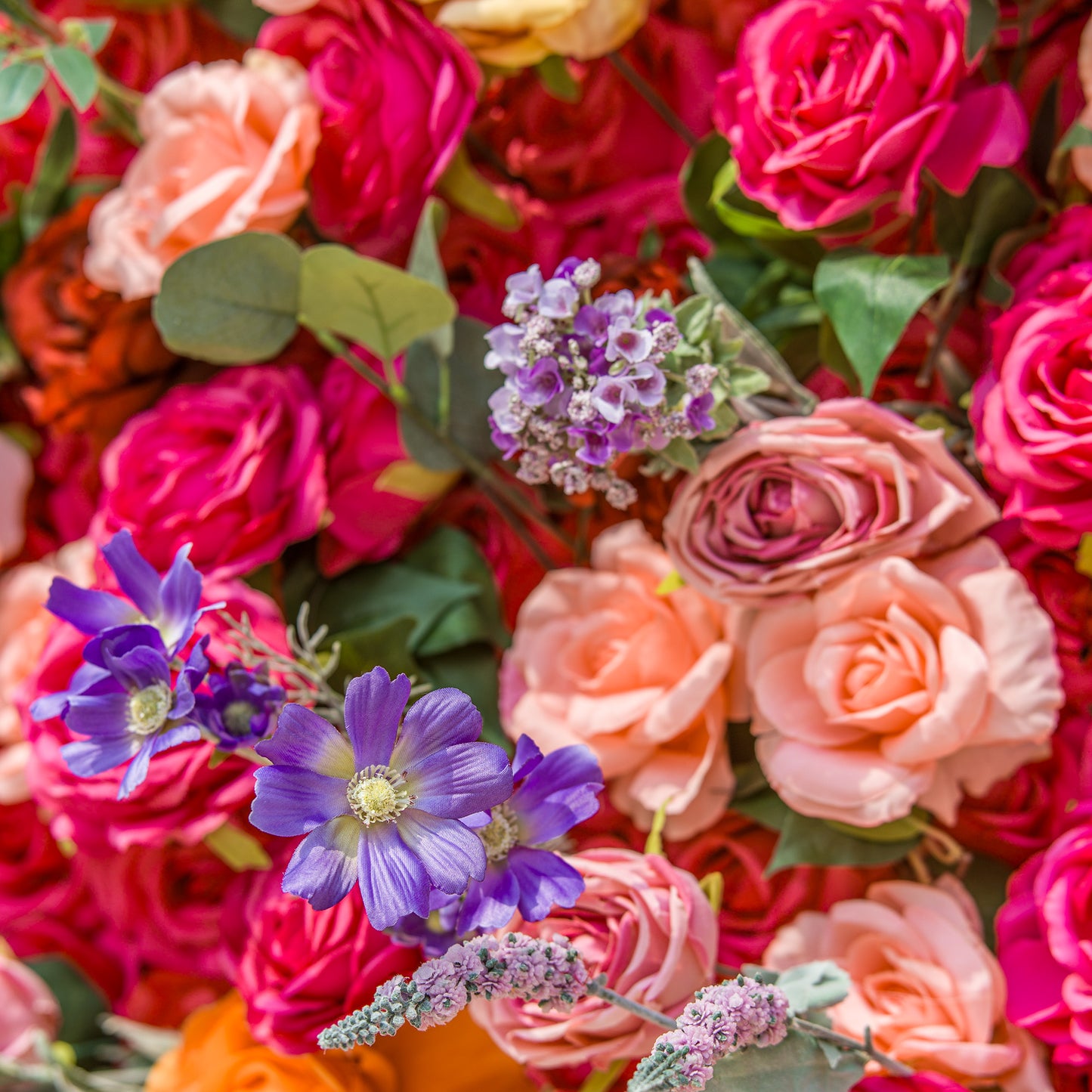 A lush floral arrangement brims with color and texture. Deep pink roses form a rich backdrop, while soft peach blooms add gentle contrast. Vivid purple flowers and delicate lavender - hued sprigs inject pops of cool tones. Green foliage weaves through, enhancing the natural, vibrant display—perfect for adding a romantic, lively touch to any space. 