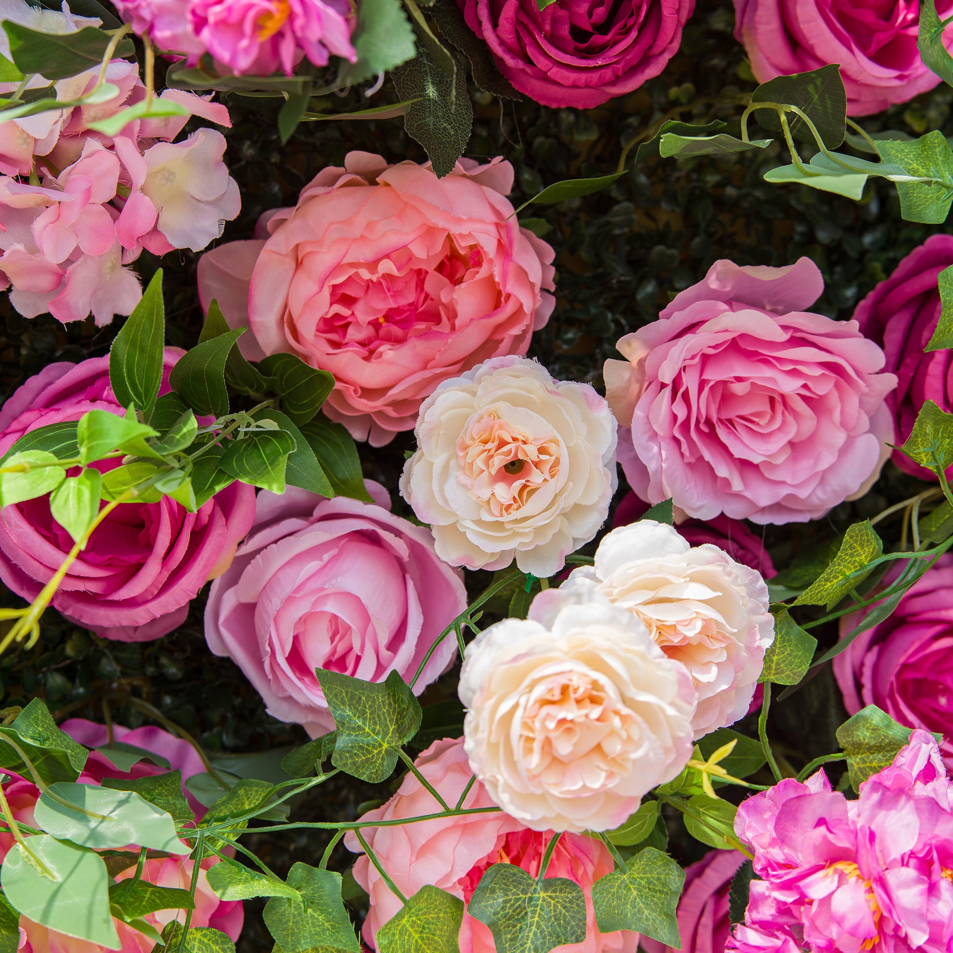 This photo showcases a lush and colorful arrangement of various roses in shades of pink, from soft pastels to vibrant hues, along with some white roses. Interspersed among the blooms are green leaves, adding a fresh contrast. The flowers appear full - petaled and well - arranged, creating a visually appealing and romantic display, likely suitable for events like weddings or garden parties. 