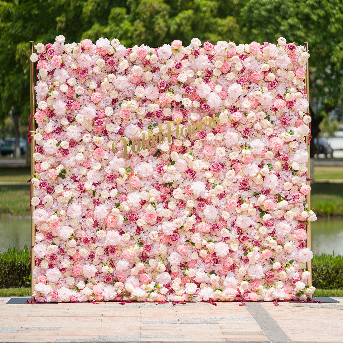 This photo from ValarFlowers showcases a large, lush floral backdrop. It is densely filled with an array of pink and white roses and peonies, creating a soft and romantic atmosphere. The backdrop is framed by golden poles, adding a touch of elegance. Ideal for weddings, bridal showers, or a “Blossoming Love” - themed event, it serves as a beautiful decorative element, exuding charm and grace. 