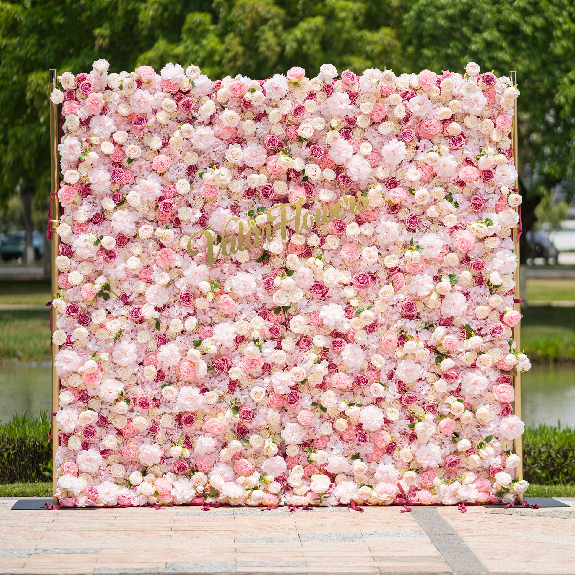 This photo from ValarFlowers showcases a large, lush floral backdrop. It is densely filled with an array of pink and white roses and peonies, creating a soft and romantic atmosphere. The backdrop is framed by golden poles, adding a touch of elegance. Ideal for weddings, bridal showers, or a “Blossoming Love” - themed event, it serves as a beautiful decorative element, exuding charm and grace. 