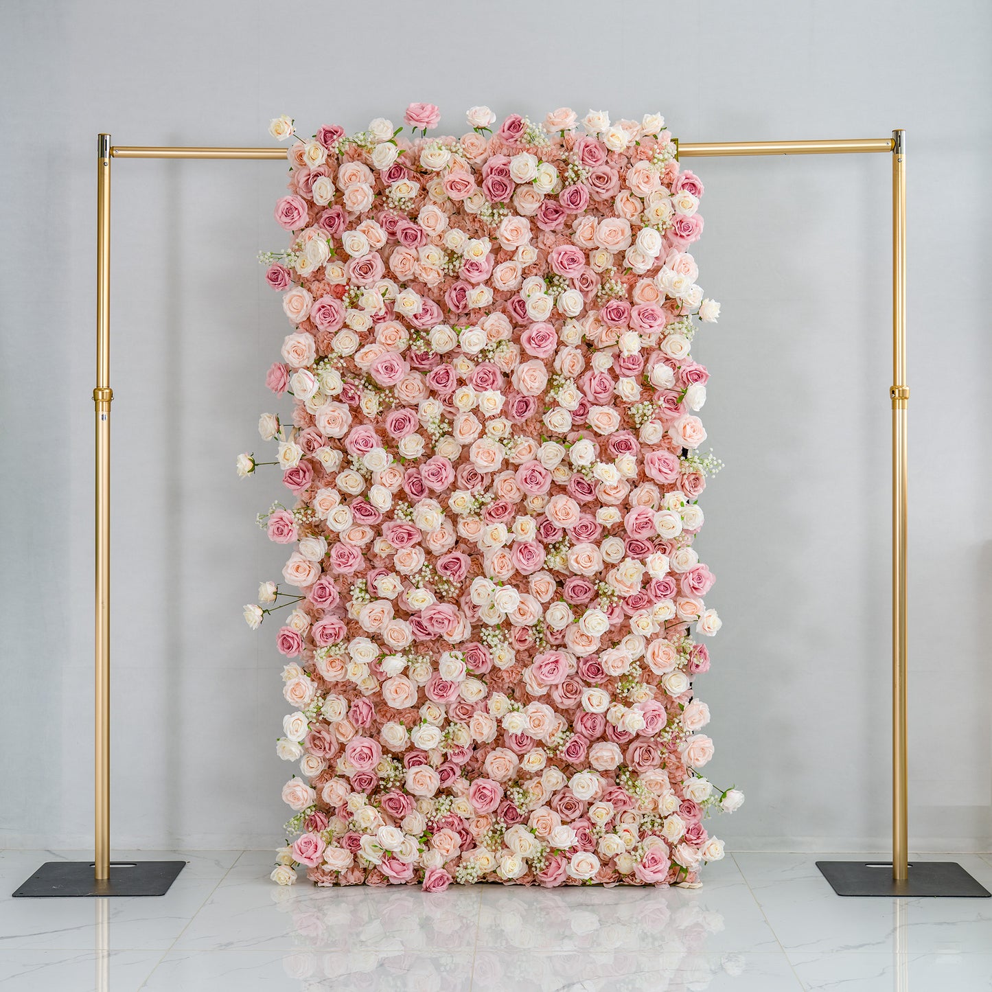 This photo showcases a completed floral backdrop. It's densely covered with pink and white roses, creating a romantic and elegant display. The backdrop is supported by a golden metal frame, standing out against the plain, light - colored background.