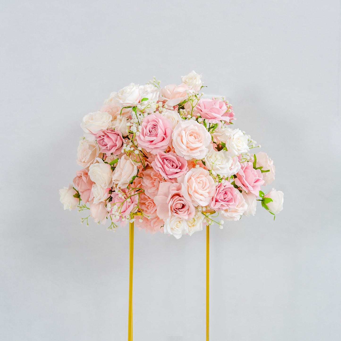 This photo showcases a beautifully arranged floral display. A lush bouquet of pink and white roses, interspersed with delicate baby's breath, forms a rounded shape. The flowers are mounted on a golden stand, which contrasts elegantly with the soft pastel hues of the blooms. Set against a plain, light - colored background, the arrangement exudes a romantic and refined charm, ideal for events like weddings or upscale parties. 