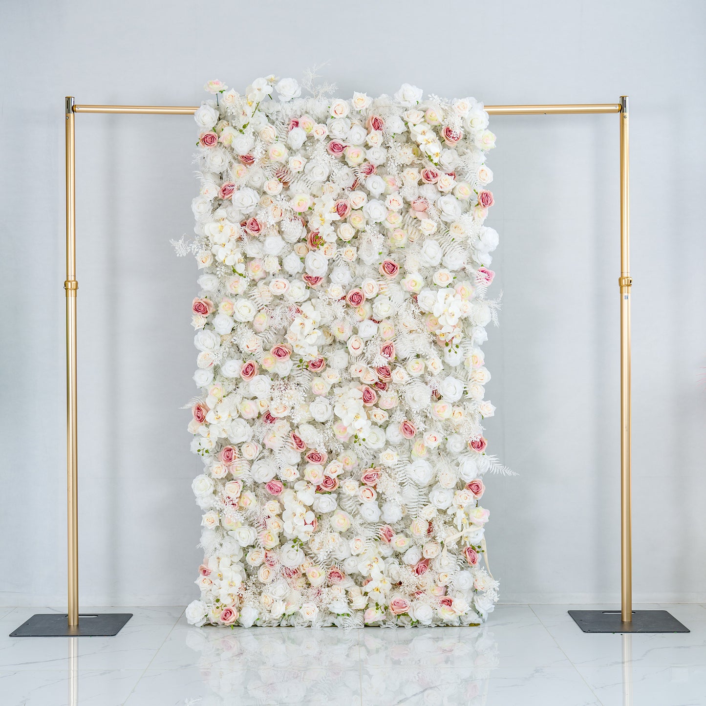 This photo showcases a 4*8ft floral backdrop mounted on a golden stand. It is densely filled with white roses, interspersed with delicate pink roses and white foliage. The soft color palette of white and light pink creates an elegant and serene atmosphere. Ideal for weddings, upscale galas, or sophisticated events, it exudes a refined, dreamy style. 