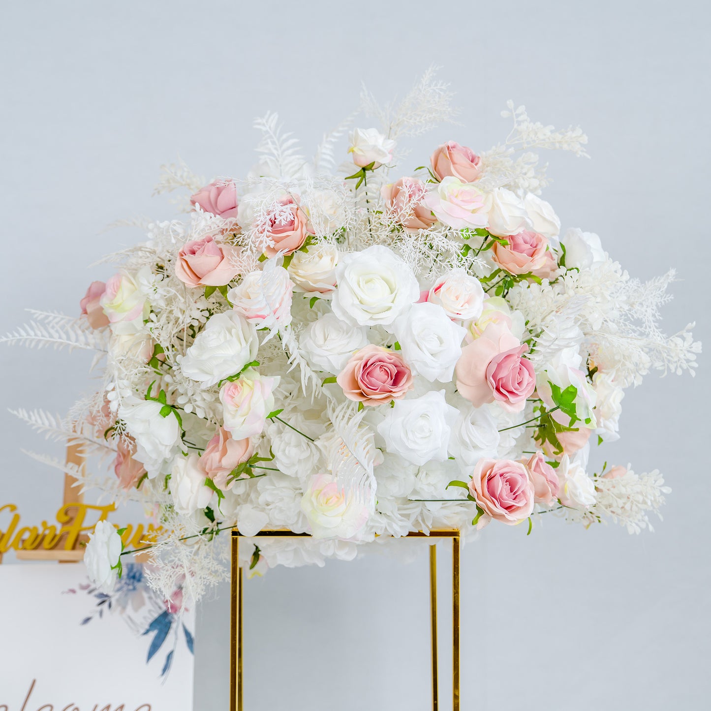 This photo showcases a lush floral arrangement, predominantly featuring white roses interspersed with delicate pink roses. The bouquet is complemented by white foliage, creating a soft and elegant aesthetic. The flowers are arranged in a golden - framed stand, exuding a refined charm. Ideal for weddings or upscale events, this arrangement exudes a dreamy, romantic style with its pastel color palette. 