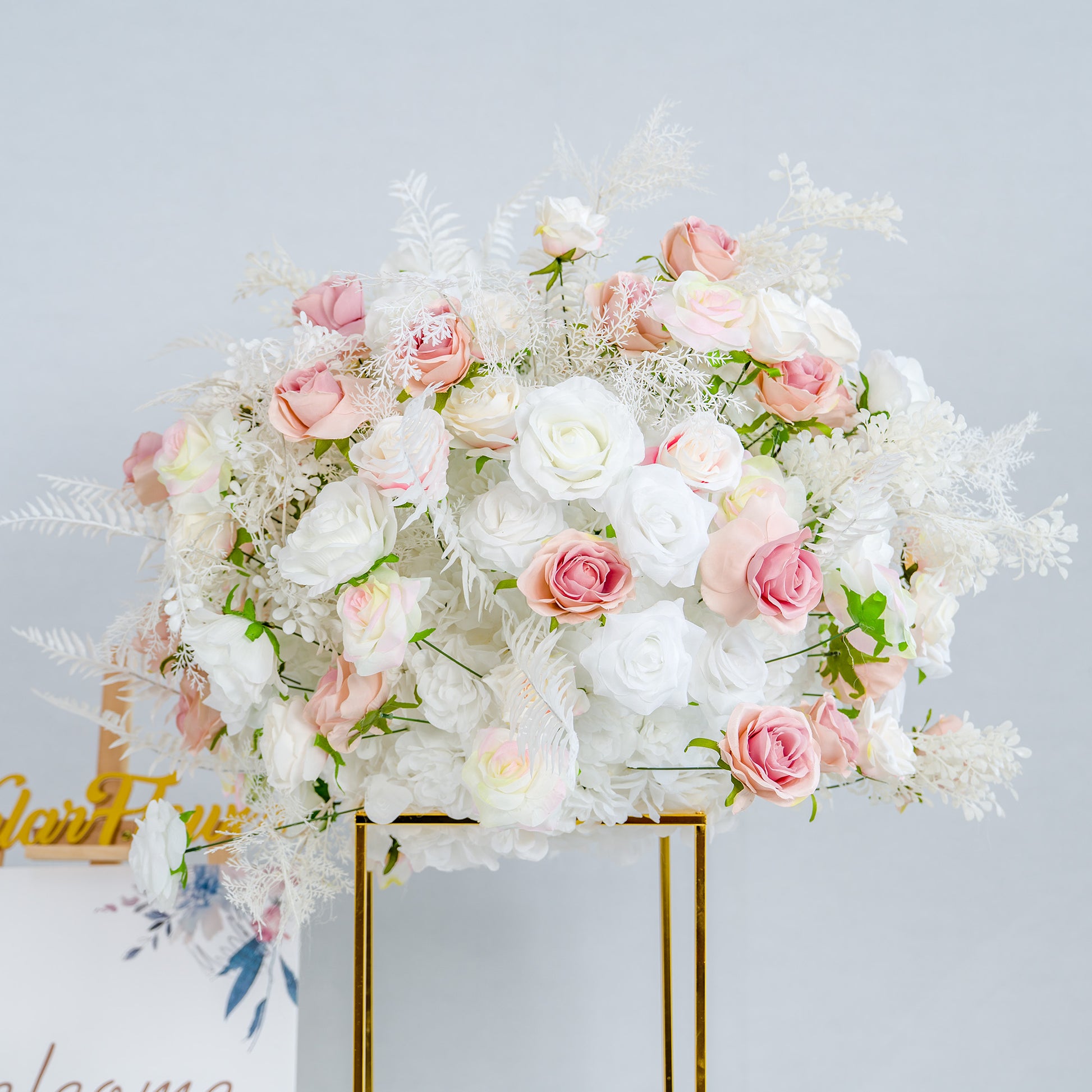 This photo showcases a lush floral arrangement, predominantly featuring white roses interspersed with delicate pink roses. The bouquet is complemented by white foliage, creating a soft and elegant aesthetic. The flowers are arranged in a golden - framed stand, exuding a refined charm. Ideal for weddings or upscale events, this arrangement exudes a dreamy, romantic style with its pastel color palette. 