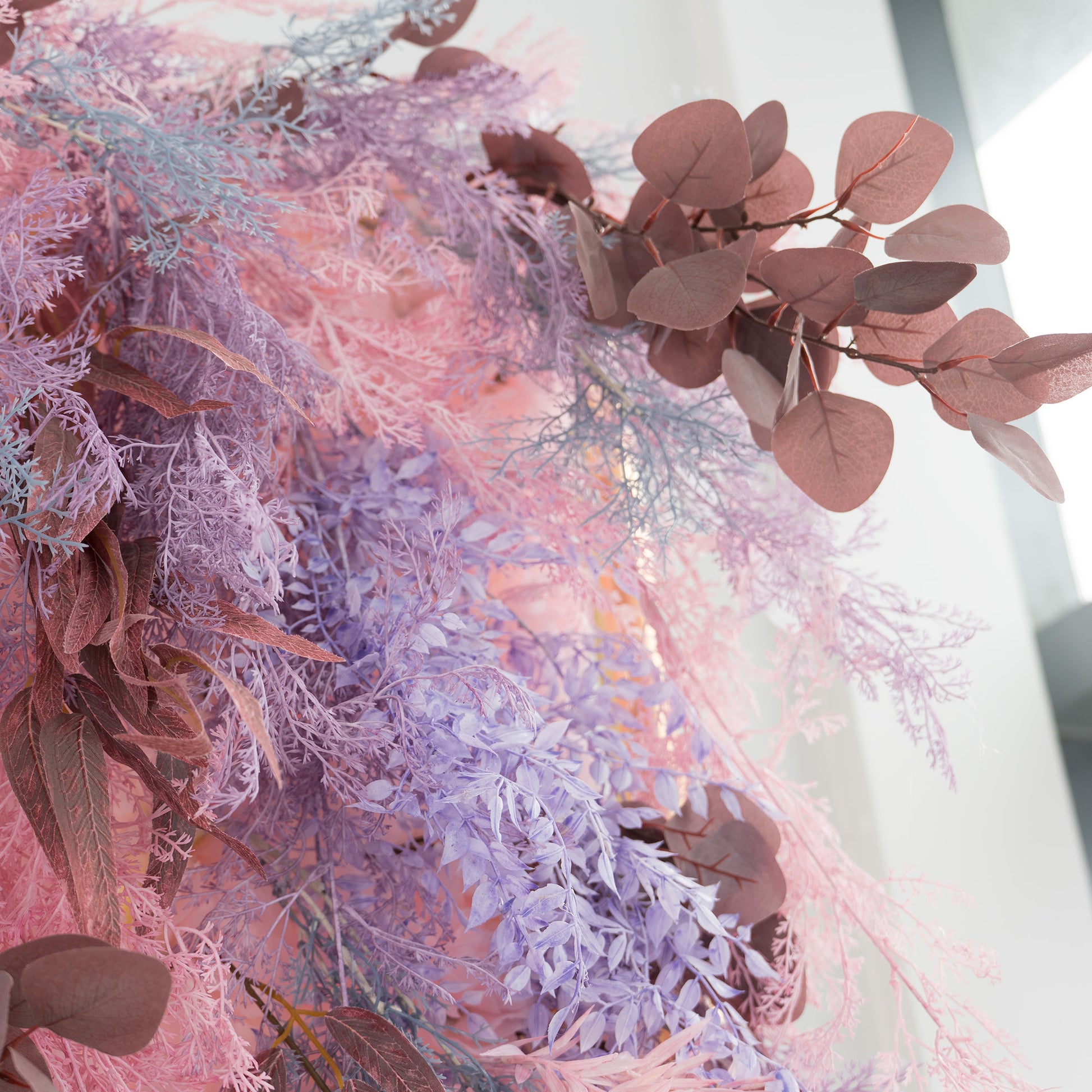 This photo showcases a close - up of a vibrant foliage backdrop. It features a mix of plants, including fluffy pink and purple foliage, and eucalyptus leaves in rich brown tones. The soft, pastel color palette creates a dreamy and romantic atmosphere. Ideal for weddings, engagement parties, or upscale events, this backdrop exudes an elegant and whimsical style, adding a touch of enchantment to any setting. 