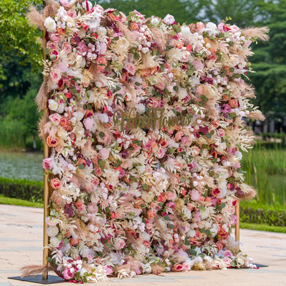 This photo showcases a large, lush floral backdrop. It is densely filled with an assortment of roses, peonies, and other blooms in soft pinks, whites, and hints of peach, interspersed with green foliage and pampas grass. The sign “ValarFlowers” is prominently displayed. Ideal for weddings, garden parties, or upscale events, it creates a dreamy, romantic atmosphere. 