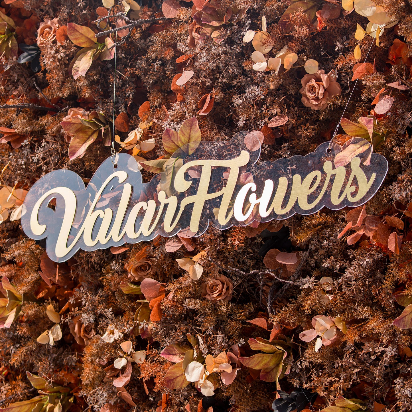 This photo features a textured floral backdrop with an array of autumn - colored flowers and foliage in shades of rust, copper, and brown. The sign “ValarFlowers” in elegant lettering stands out against the rich hues. Ideal for events like an “Autumn Rustic” wedding or a harvest - themed gala, it exudes warm, seasonal charm. 