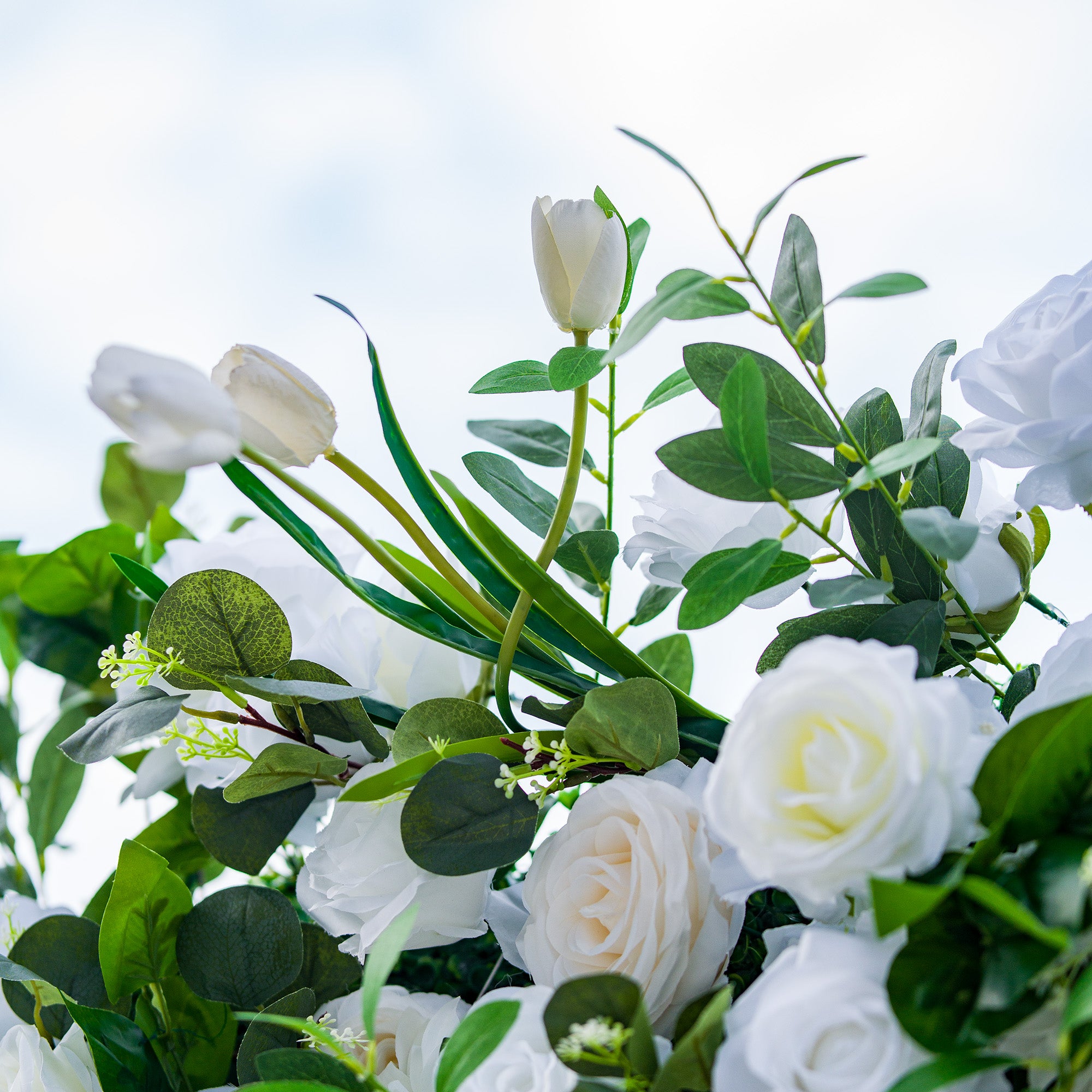 This photo showcases a lush arrangement of white roses and tulips, complemented by rich green foliage. The delicate white blooms create a serene and elegant atmosphere. Ideal for events like a “White Elegance” baby shower or a refined garden tea party, it exudes a sense of purity and grace, perfect for intimate and sophisticated gatherings. 